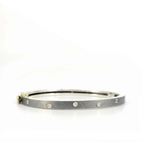 Front view oxidized sterling silve hinged bangle with scattered inset diamonds and a 18k yellow gold clasp