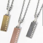 three separate rectangular dog tag style pendants on chains, left one is our item in stock and it has a gold overlay with 8 inset diamonds up the right side and a, inlayed diamond diamond bale