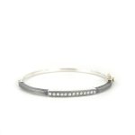 2.5MM. Oxidized silver hinged bangle featuring an 18k gold push button style clasp and set with 13 white diamonds 0.13ct total combined diamond weight.