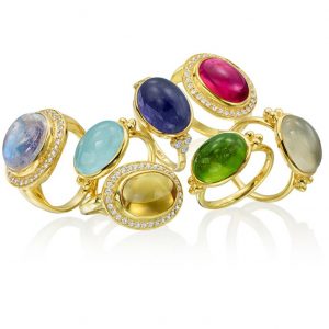 displace of multiple thin banded gold rings with various semiprecious cabochon gemstones centerpieces, three of the rings have a halo of small round bezel set diamonds around the stone