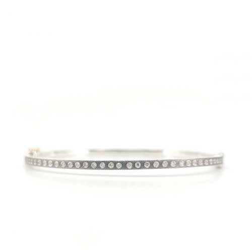 2.5MM. Silver hinged bangle featuring an 18k gold push button style clasp and set with 35 white diamonds 0.35ct total combined diamond weight.