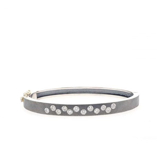 6MM. Silver hinged bangle featuring an 18k gold push button style clasp and set with 12 white diamonds 0.60ct total combined diamond weight.
